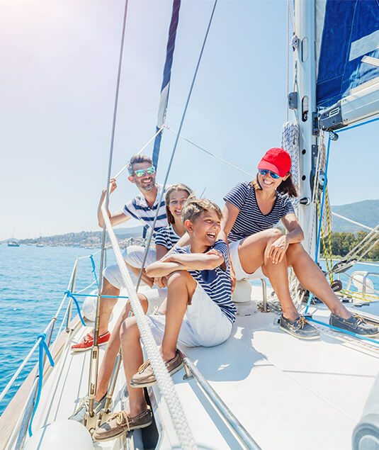A smiling family is sitting on a sailboat on the water